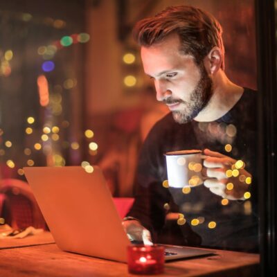 man holding mug in front of laptop