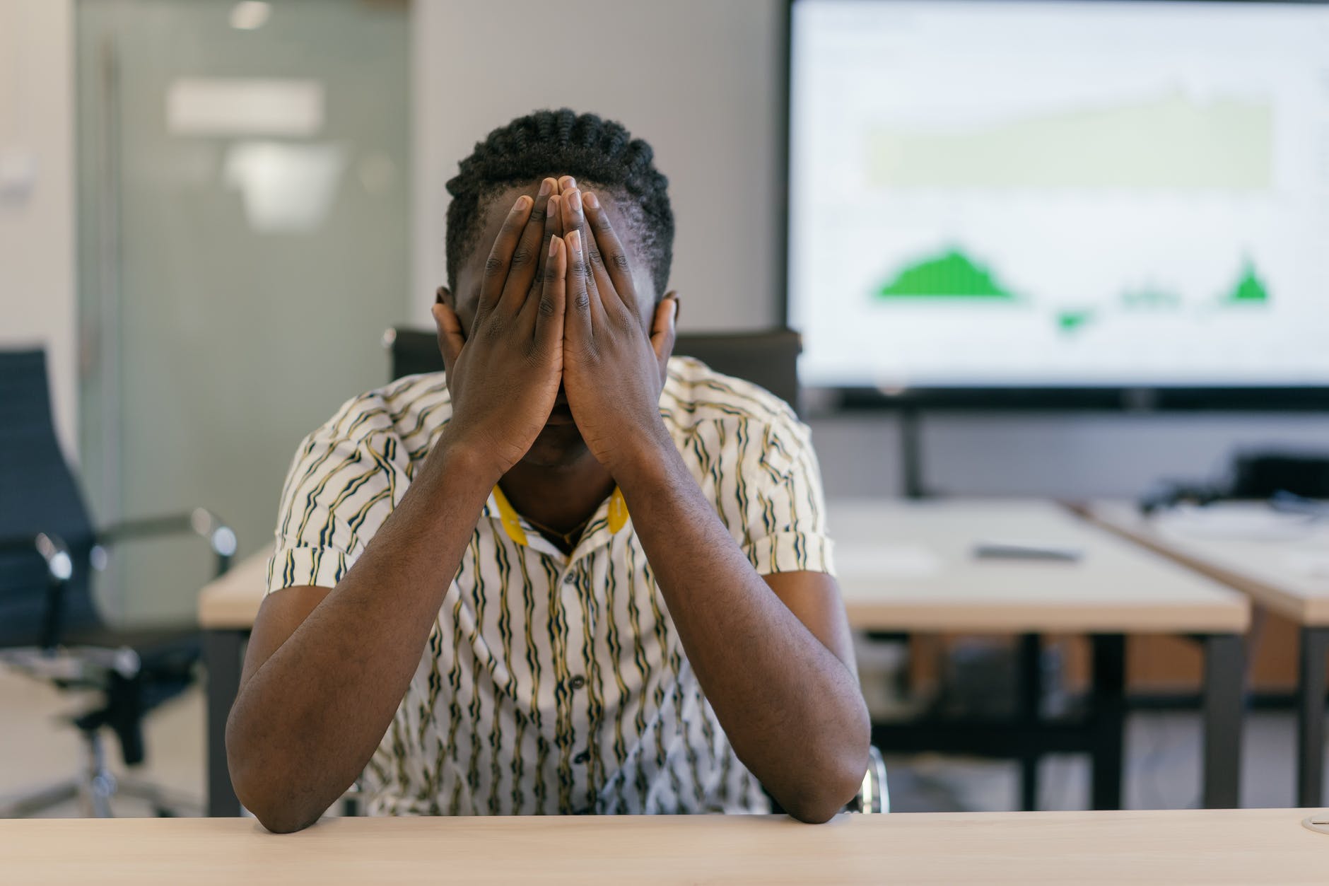 man in white and black shirt covering his face