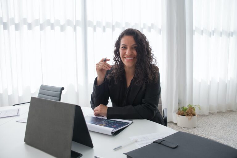 a woman in black blazer smiling while sitting near the table