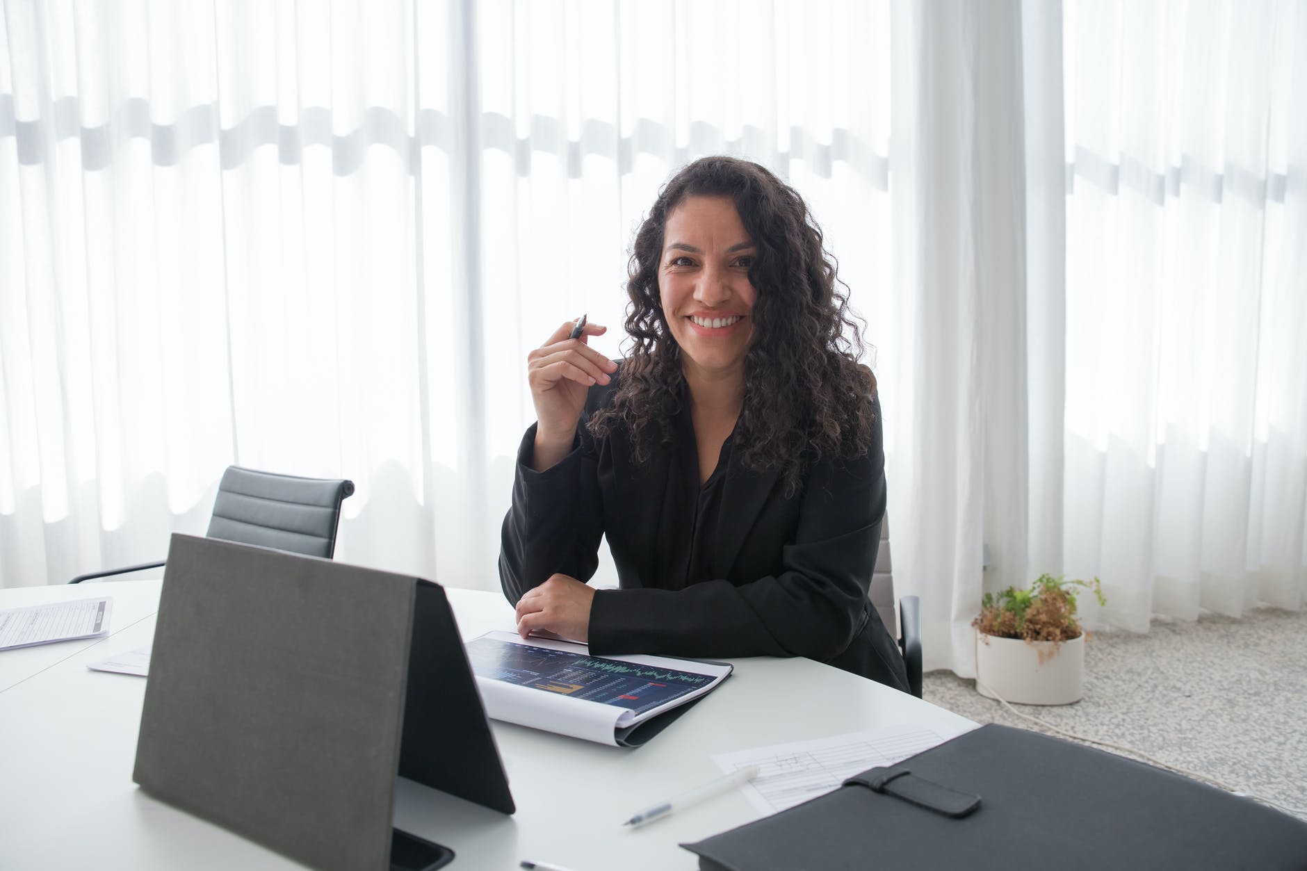 a woman in black blazer smiling while sitting near the table